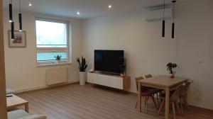 a living room with a table and a television at Apartmán Istebné luxure in Istebné
