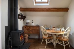 a dining room with a table and a wood stove at The Damson Barn in Biddulph