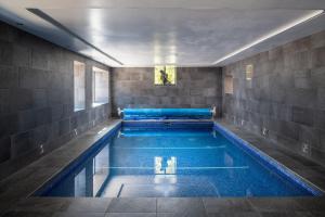 a large swimming pool in a building with a blue tub at The Damson Barn in Biddulph