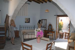 two women in a bedroom with a table with a vase of flowers at Lito House in Skarinou