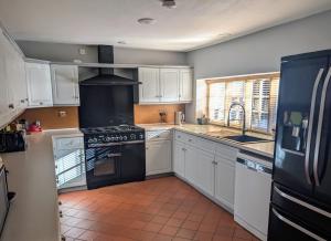 a kitchen with white cabinets and a black stove top oven at The Lawns House in Holt