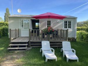 a small house with two chairs and an umbrella at Camping 3 étoiles - Piscine - ccbfghc in Mamers