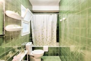 a green tiled bathroom with a toilet and a sink at Estartit Centro in L'Estartit +22 photos
