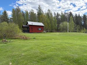 a red barn in the middle of a green field at Mosters hus in Gansbyn