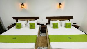 two beds in a room with green pillows at Aloria Sigiriya in Sigiriya