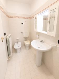 a white bathroom with a sink and a toilet at PETRONIA TRILO VISTA MARE - Agenzia Cocal in Caorle