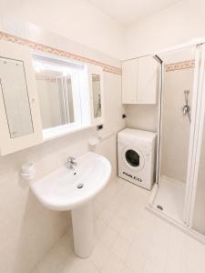a bathroom with a sink and a washing machine at PETRONIA TRILO VISTA MARE - Agenzia Cocal in Caorle