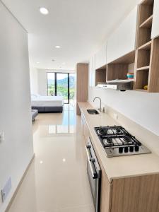 a white kitchen with a stove and a bed at Reserva del Mar II, Aparta suite cerca de la playa in Gaira