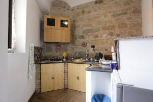 a kitchen with wooden cabinets and a stone wall at Aurora Bed and Breakfast in Santo Stefano di Camastra