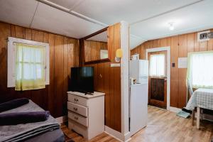 a room with a bed and a tv and a refrigerator at 1-Bedroom Cottage #2 - Ambleside in Kawartha Lakes
