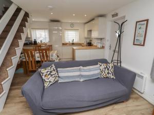 a living room with a blue couch and a kitchen at 22 Longstone Park in Chathill