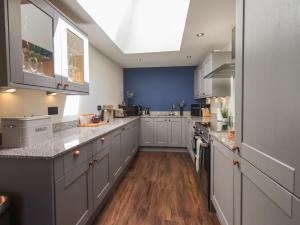 a large kitchen with white cabinets and wood floors at Fogga Croft in Skipton