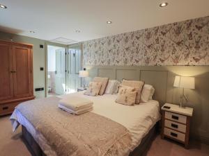 a bedroom with a bed with white sheets and floral wallpaper at Fogga Croft in Skipton