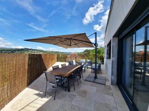 a patio with a wooden table and chairs and an umbrella at Apt Belvedere in Apt