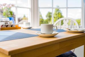 a wooden table with two cups and plates on it at Radcliffe Guest House in Ross on Wye