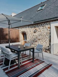 a patio with a table and chairs and an umbrella at Charmant T2 - 4 couchages à 15mn de la mer in Merlevenez
