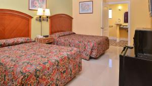 a hotel room with two beds and a flat screen tv at Magnuson Hotel Blythe in Blythe