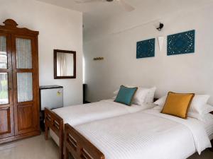 two beds in a room with white walls at Skylark Resort in Colva