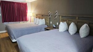 a hotel room with two beds with white pillows at Magnuson Hotel Blythe in Blythe