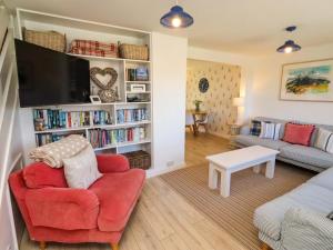 a living room with a red chair and a tv at Dunford Cottage in Bamburgh