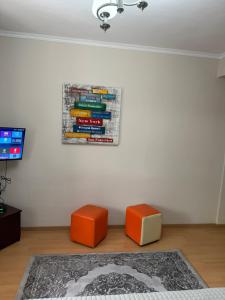 a room with two orange stools and a painting on the wall at Cozy City Studio in Gjirokastër