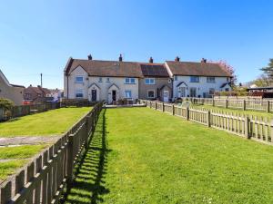 a house with a fence in front of a yard at Dunford Cottage in Bamburgh