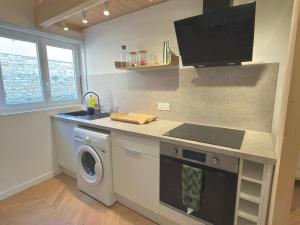 a kitchen with a stove and a washing machine at Le Perchoir in Beauregard