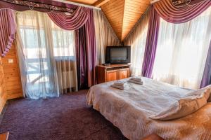 a bedroom with a bed and a tv and windows at Садиба "Едем" in Mykulychyn +14 photos