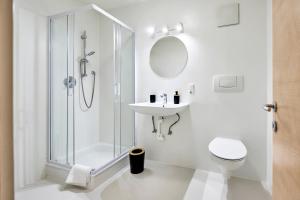 a white bathroom with a shower and a sink at Ladurnhof in Silandro
