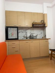 a kitchen with wooden cabinets and an orange couch at Cozy City Studio in Gjirokastër