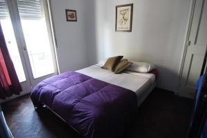 un letto con piumone viola in una camera di mate! Hostel a Córdoba