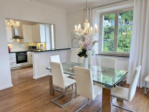 a dining room with a glass table and white chairs at Villa Grande Dame by Fewotessin in Minusio