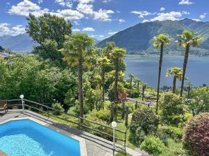 a swimming pool with palm trees and a lake at Villa Grande Dame by Fewotessin in Minusio