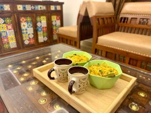 a table with two cups of coffee and a tray of food at Tri Riverfront Homestay in Udupi