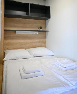 a white bed with two white towels on it at Rilux Mobile Home "Camping Pirovac" in Pirovac