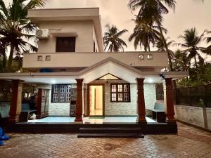 a house with palm trees in front of it at Tri Riverfront Homestay in Udupi