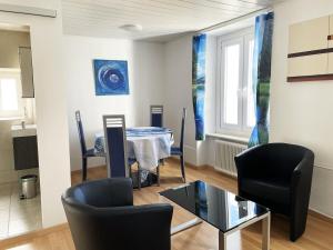 a living room with a table and chairs and a window at 1 appartement au centre de Saignelégier in Saignelégier