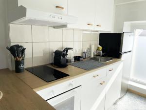 a white kitchen with a sink and a microwave at 1 appartement au centre de Saignelégier in Saignelégier