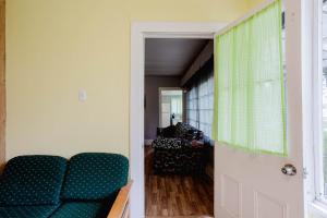 a living room with a green couch and a door at 3-Bedroom Cottage #7 - Ambleside in Kawartha Lakes