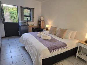 a bedroom with a large bed with towels on it at In Vrede in George