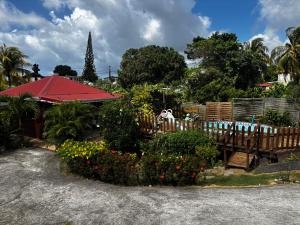 a garden with a red umbrella and some flowers at Cerise in Sainte-Anne