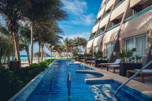 a swimming pool next to a building with palm trees at Flamingo Cancun All Inclusive in Cancún
