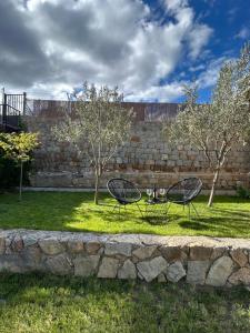 two chairs sitting in the grass next to a stone wall at El jardín de las piedras in La Colilla