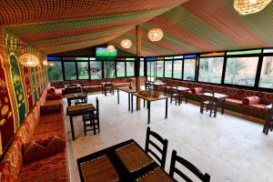 an empty restaurant with tables and chairs and windows at Maison d hôtes Dar Charach in Ouarzazate