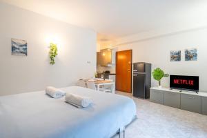 a white bedroom with a bed and a kitchen at Lake Como - Front Station - Lake at 2 min - Wifi in Lecco