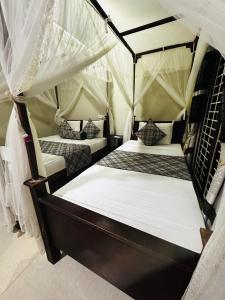 two beds in a room with mosquito nets at The Sigiriya Rock Gate Chalet in Sigiriya +71 photos