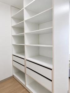 a walk in closet with white shelves at SunsetSkylineApartment in Nivy