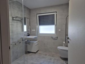 a bathroom with a toilet and a sink and a window at Apartment Natalija A2 ground floor in Krk +22 photos