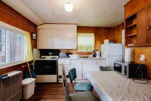 a kitchen with white cabinets and a table with chairs at Ambleside - 2-Bedroom Cottage #8 in Kawartha Lakes