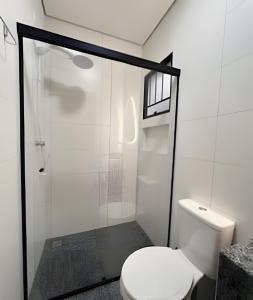 a bathroom with a toilet and a glass shower at Santorini Urban Studio • conforto e estilo in Londrina